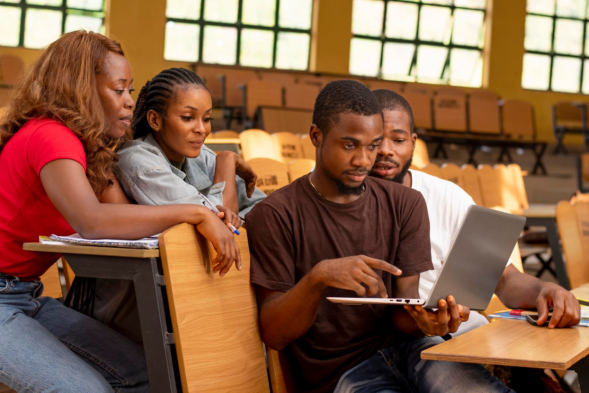Students collaborating around a laptop in a Ghanaian lecture hall